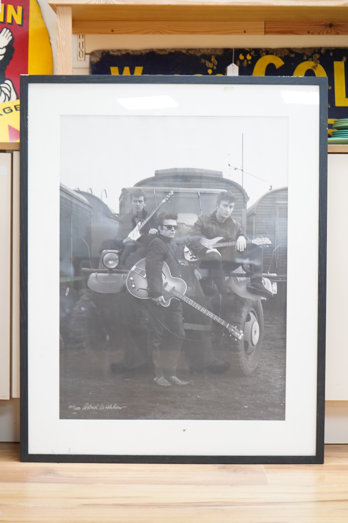 A framed and mounted black and white photograph of The Beatles by Astrid Kirchherr, showing John Lennon, George Harrison and Stuart Sutcliffe posing with guitars in front of a Land Rover, limited edition 341/500 and sign